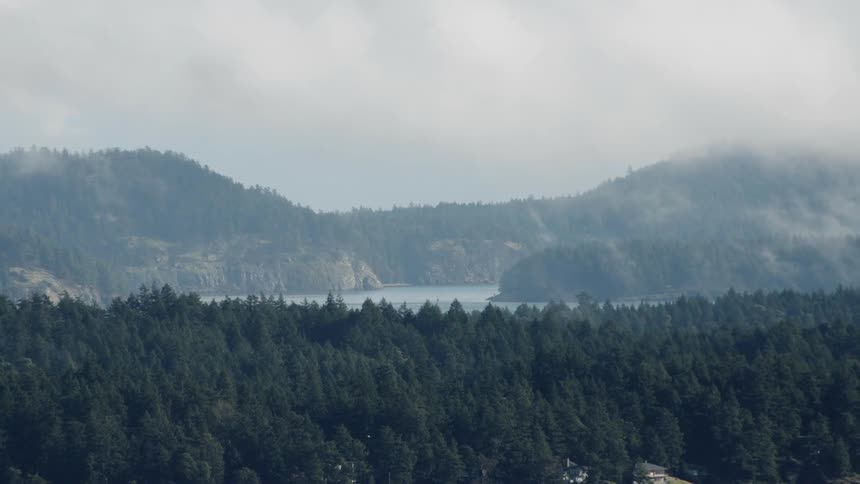 Clouds move over the forest, lake and hill tops