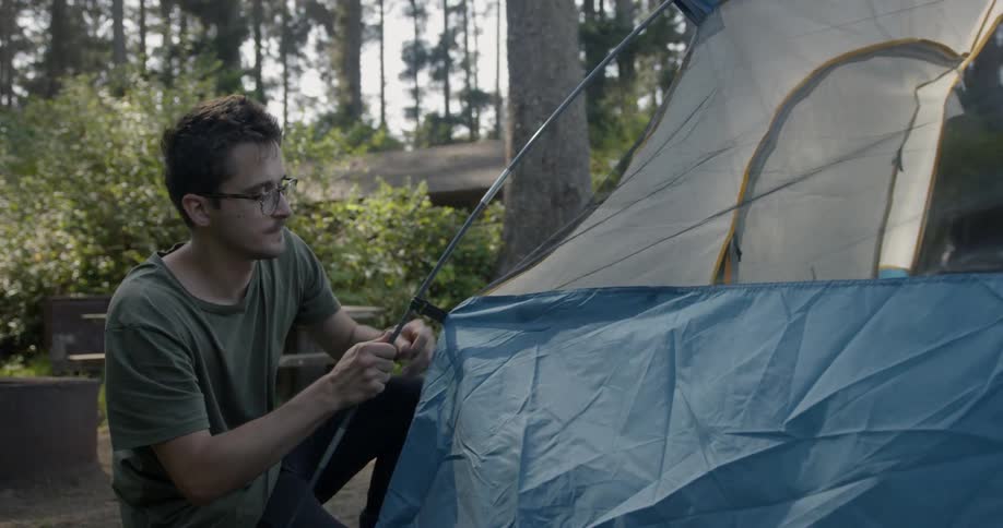 A man pitches a tent in the woods