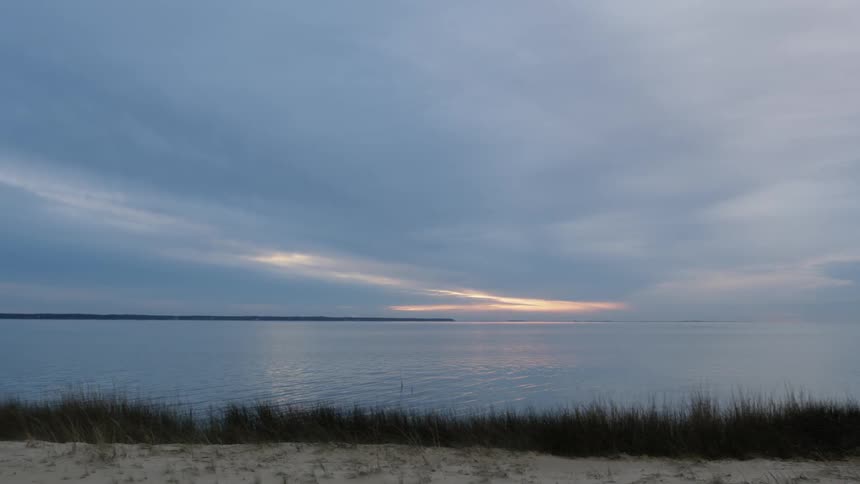 The sun is setting in the thick clouds over the lake