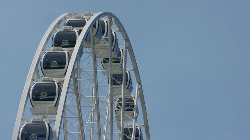A giant ferris wheel is turning on a sunny day