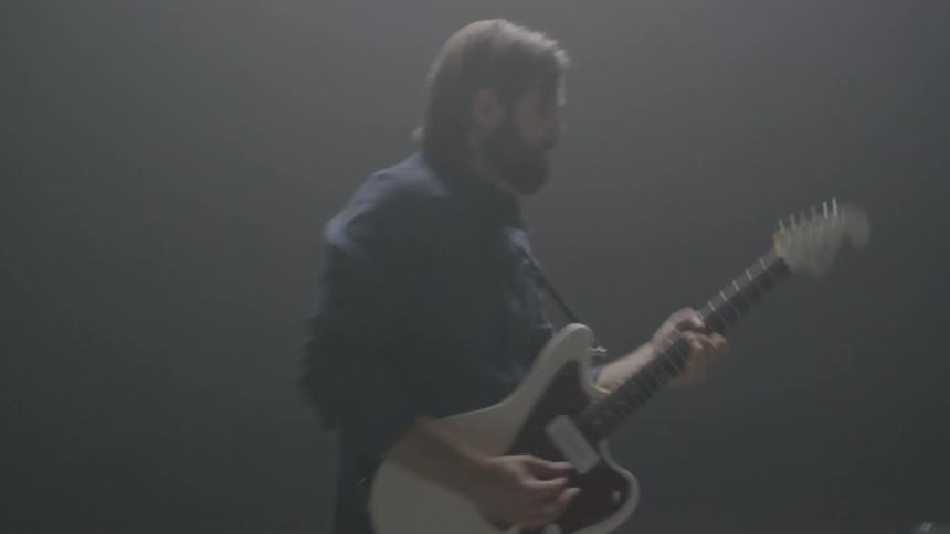 A man is dancing as he plays the guitar