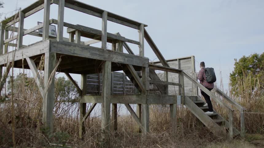A man walks up steps to a wooden platform