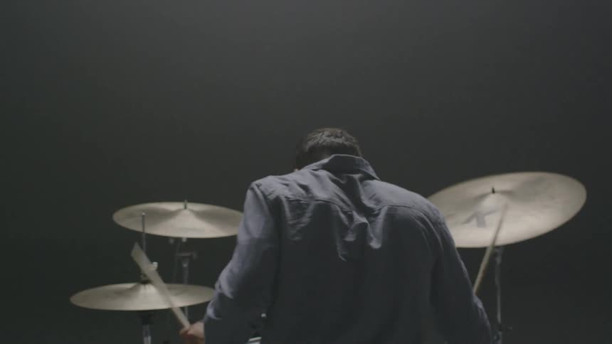A man is playing the drums in an empty studio