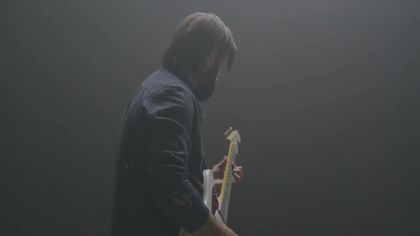 A man plays guitar in a dim room