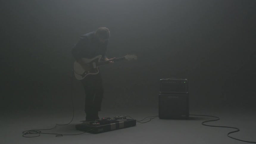A man plays an electric guitar in a hazy room
