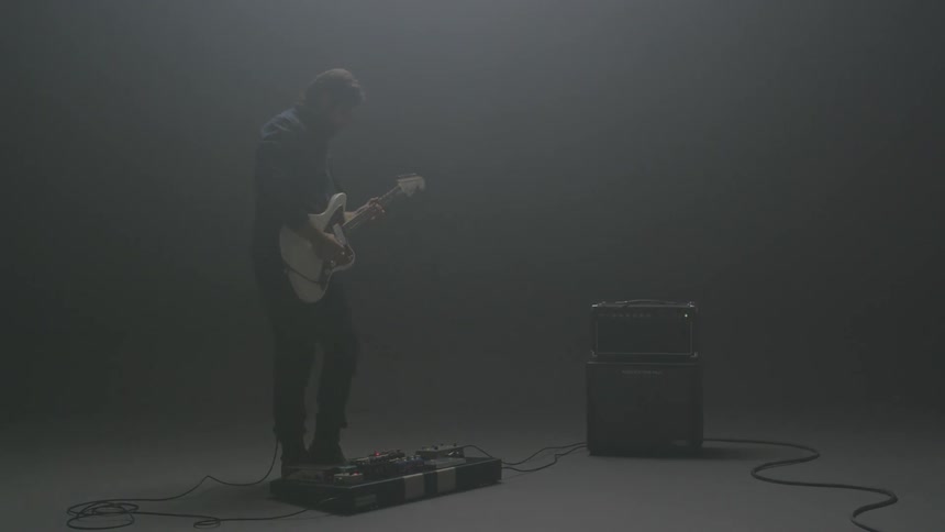 A man plays guitar in a dim room