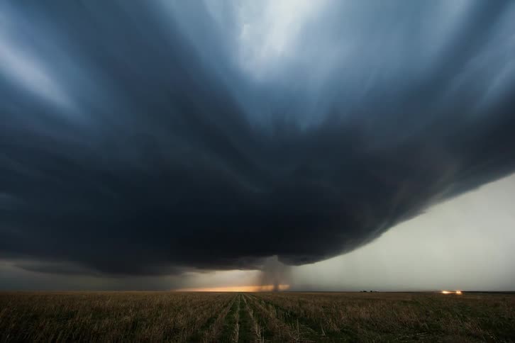 A storm brews over a large crop field