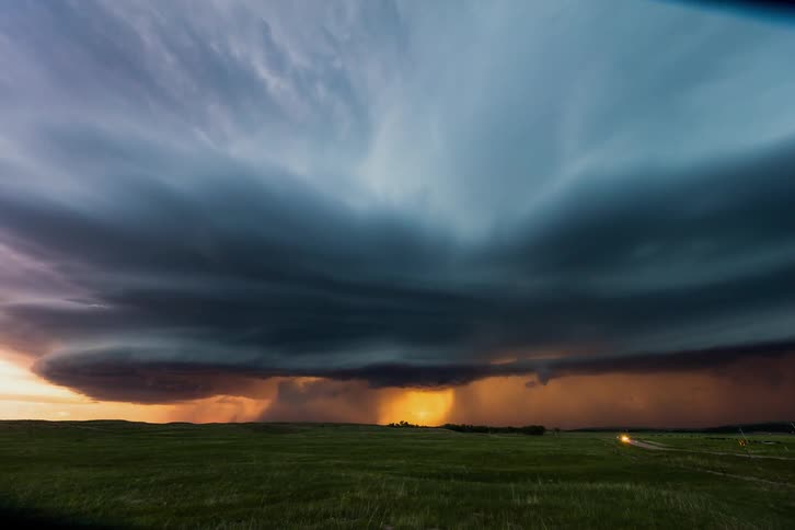 A storm brews over an open grass field