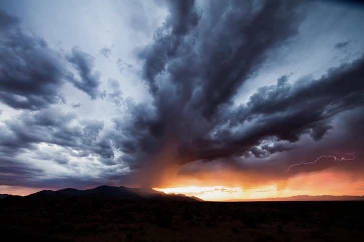 Storm clouds are moving over a hill at dusk