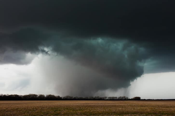 A tornado is blowing across a field during the day
