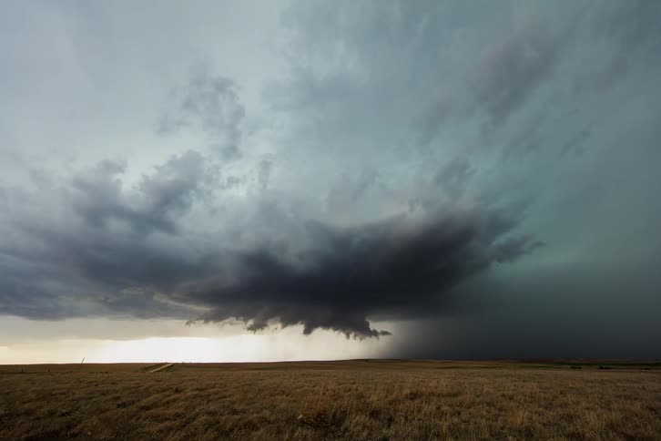 Clouds float over a rural field during a rainstorm