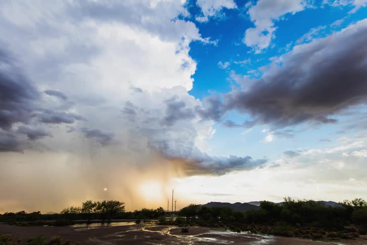 The rain is pouring over the hills in the distance at sunset