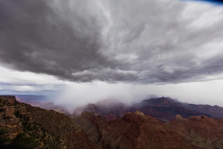 Storm clouds and rain move over rocky peaks