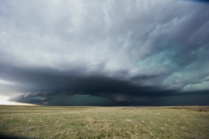 A storm brews over an open grass field