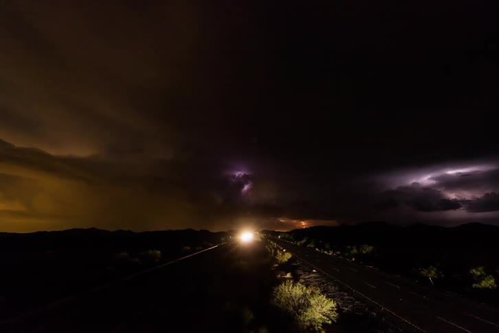 Lightning strikes in a large storm over a road