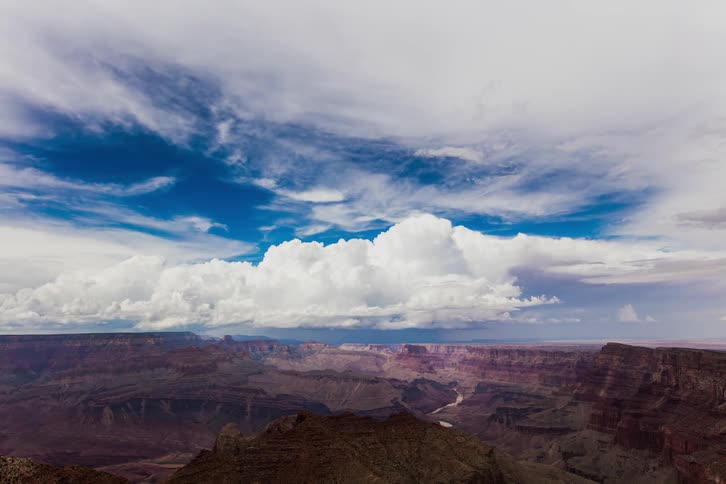 Clouds are billowing and drifting over a canyon during the day