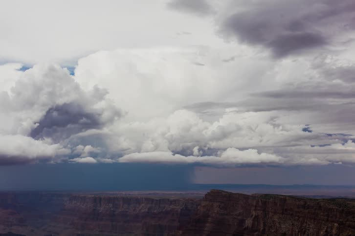 Clouds are billowing as they move across a desert during the day