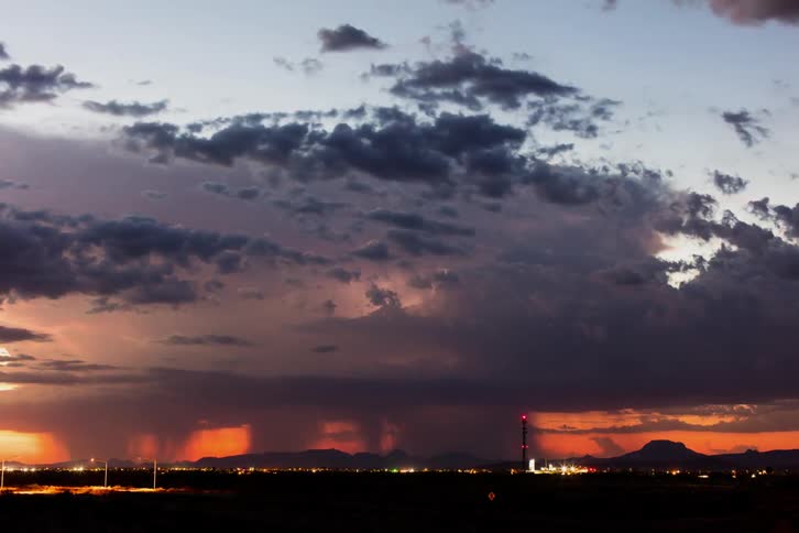 The sun setting with dark clouds over a busy city