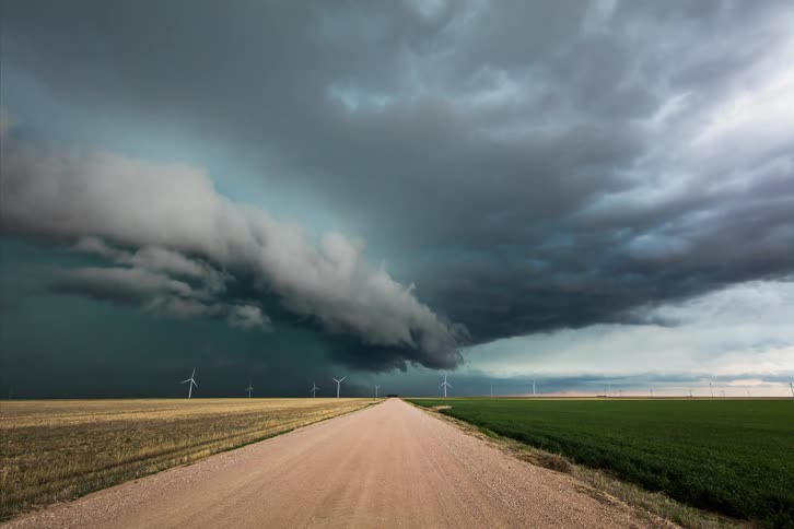 Storm clouds gather over fields and wind turbines