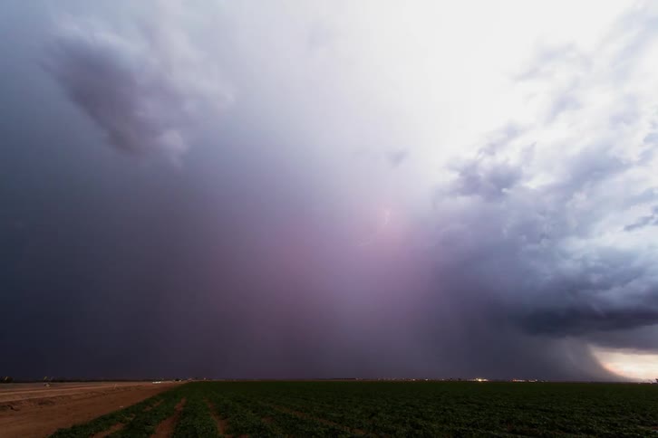 A lightning storm is blowing across a desert landscape at dusk