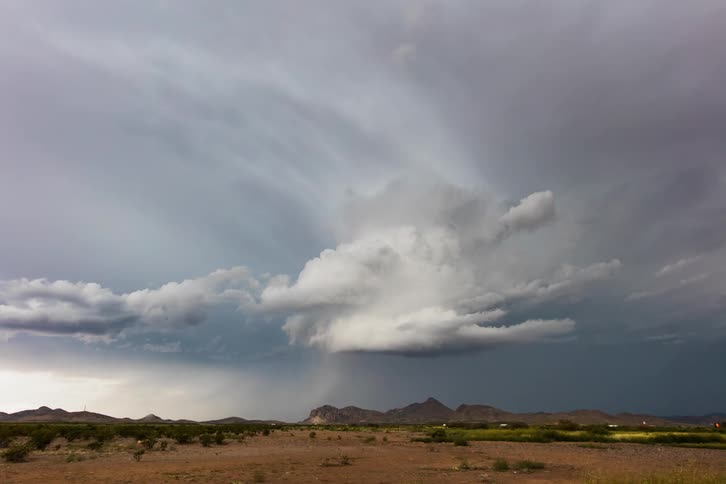 A storm is moving across a desert road in daylight