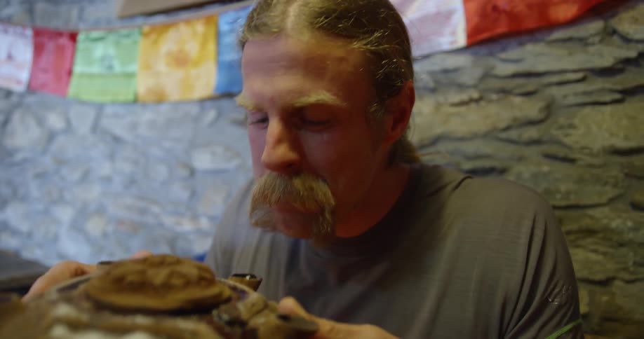 A man takes a sip from a large shell like dish