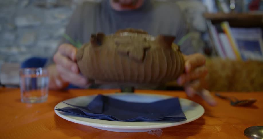 A man picks up a traditional bowl and drinks from it