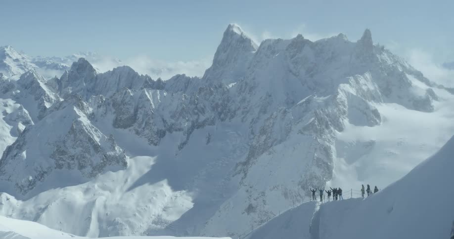 A group of people stand atop a snow mountain