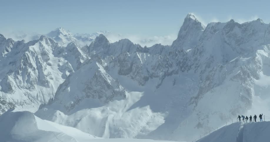 Climbers look out to a vast mountain range covered with snow Aiguille du Midi