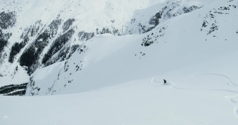 A person skis down the snow covered slope below