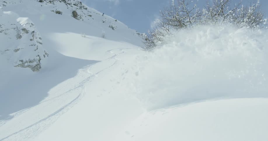 The snowboarder turns throwing snow all over camera