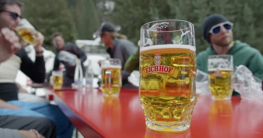 A group of men drink beer together out in the snow