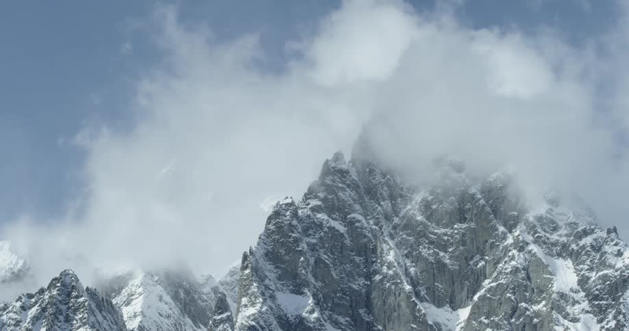 The snow blows over the mountains causing fog