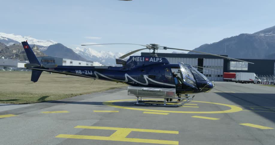 Two people stand beside as helicopter on a launch pad