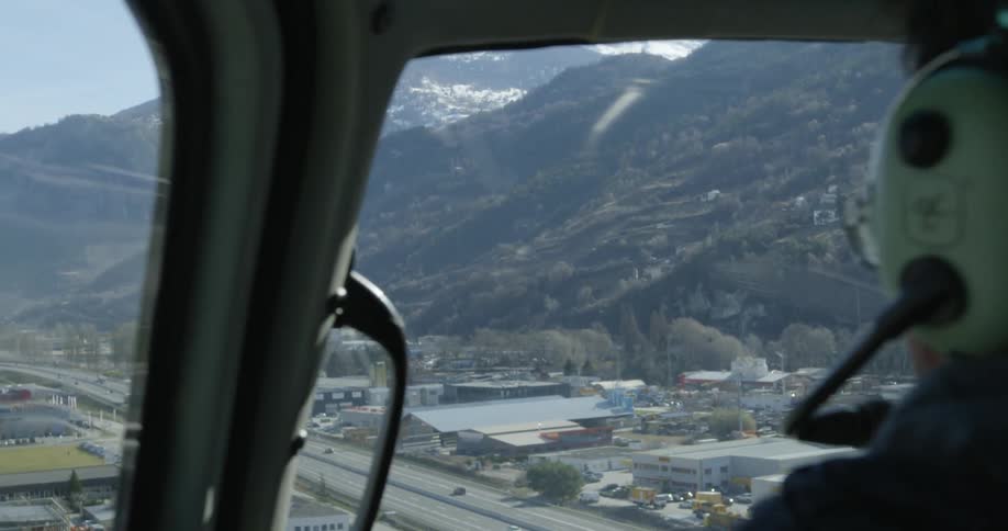 A man flies a helicopter over a city highway