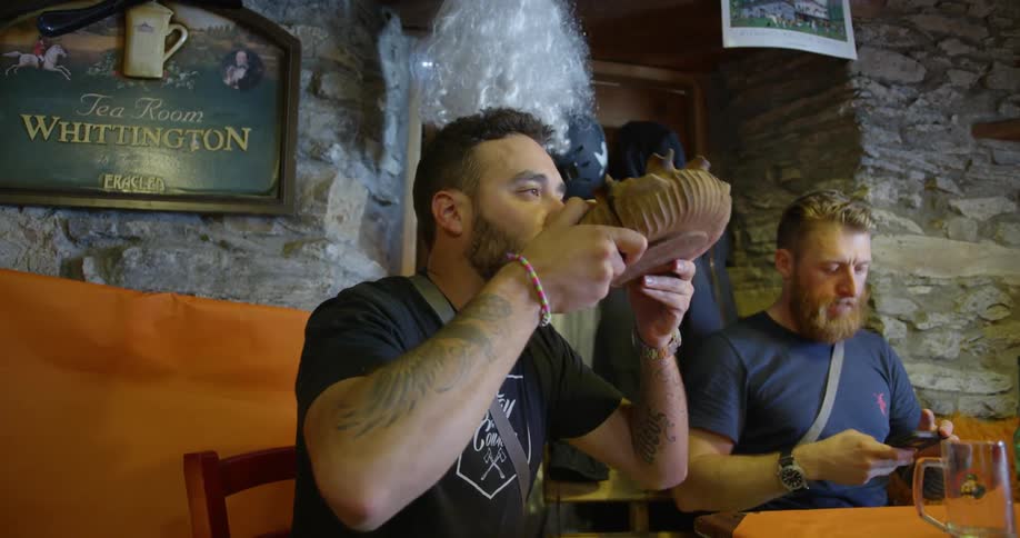 A man takes a sip from a large shell like dish