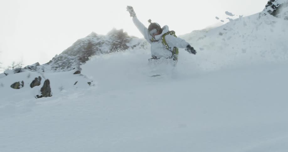 A snowboarder plows through fresh powder on a slope