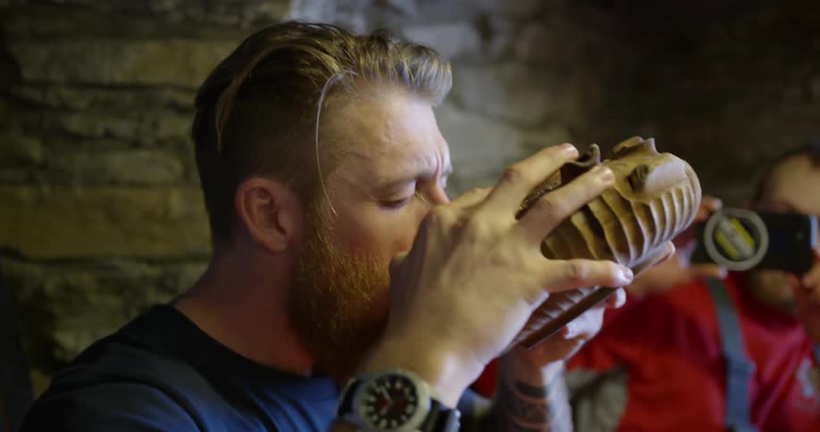 A man takes a drink from a circular dish