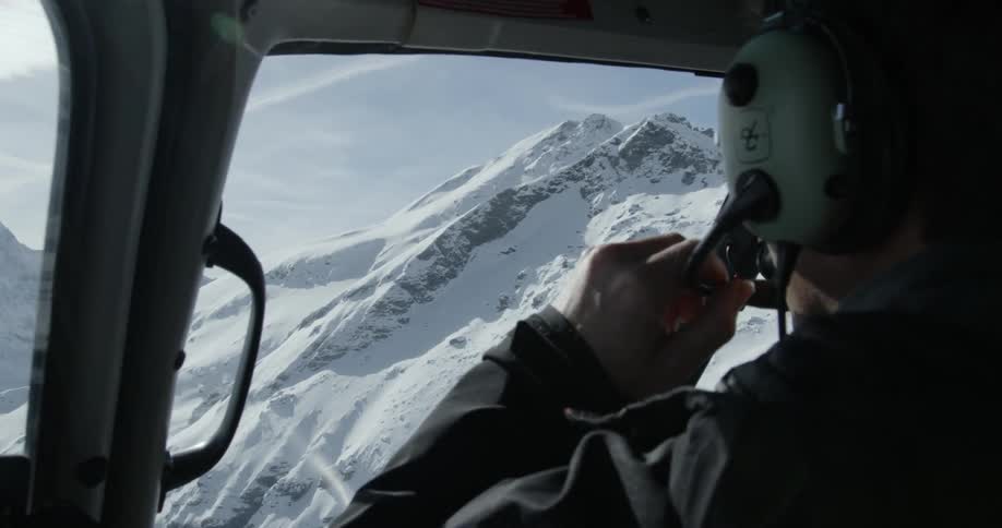 A helicopter pilot talking over radio in snowy mountains
