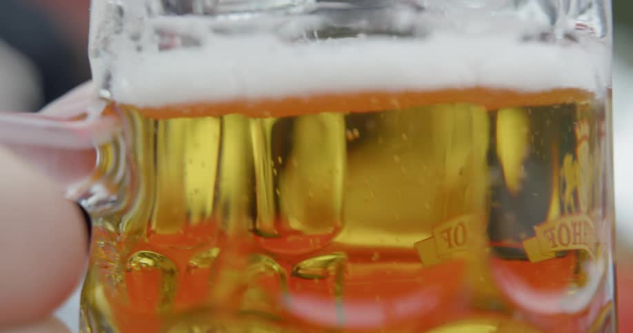 A person lifts of a full mug of beer