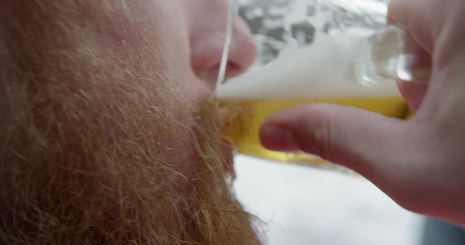 A man takes a large sip of beer