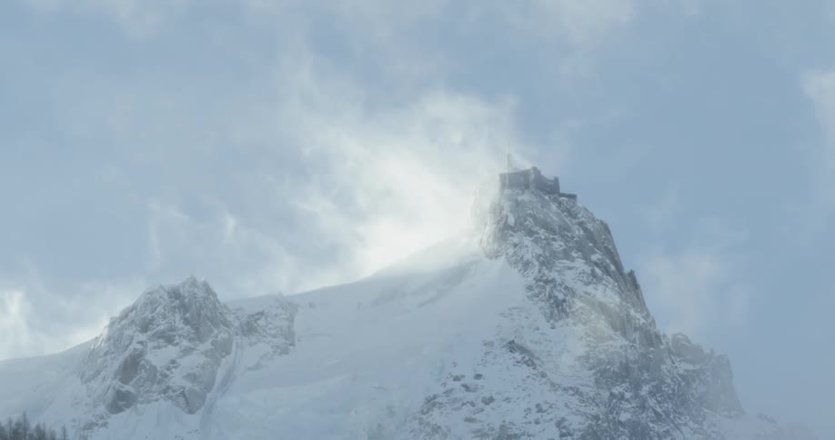 Snow is blown off the top of the mountain
