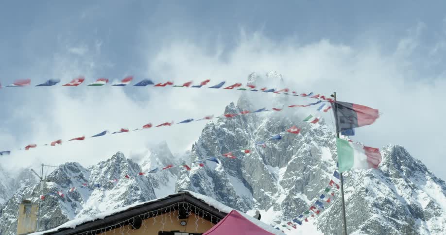 The gusting wind blows banners and flags hung outside of a cabin