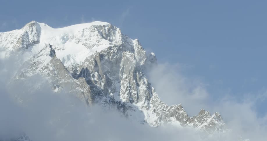A snowy mountain appears through thick fog