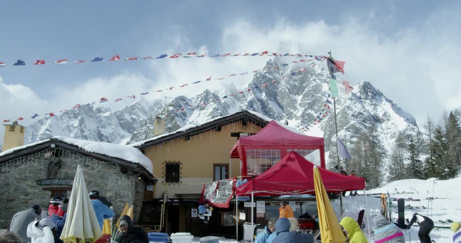 People are milling about in a ski resort on a windy day