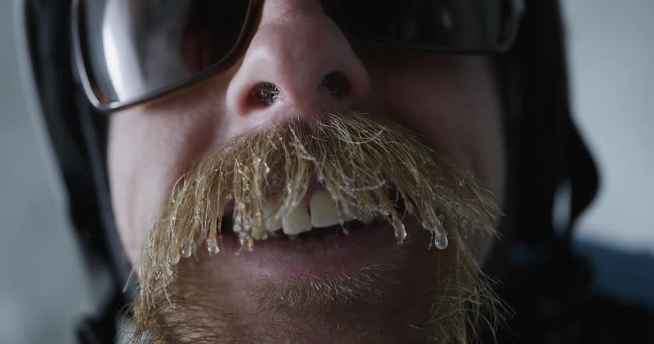 A man smiles with ice and water hanging from his mustache