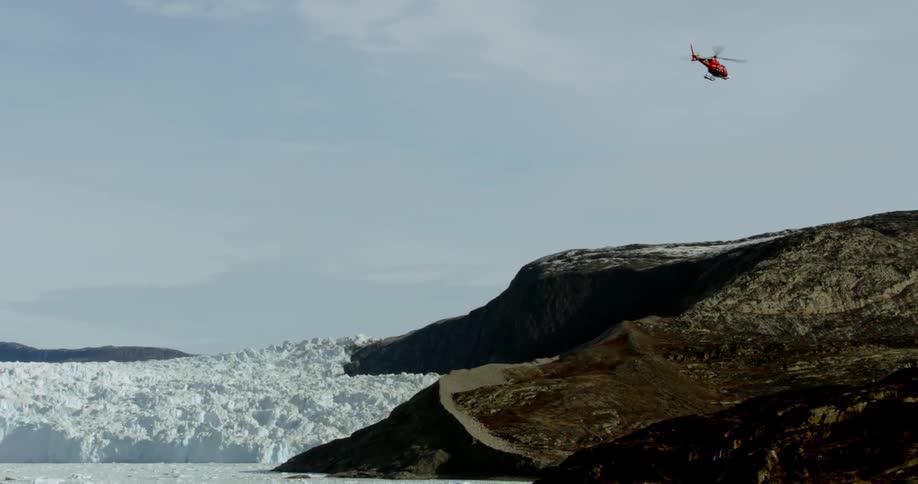 A helicopter is flying over a frozen tundra