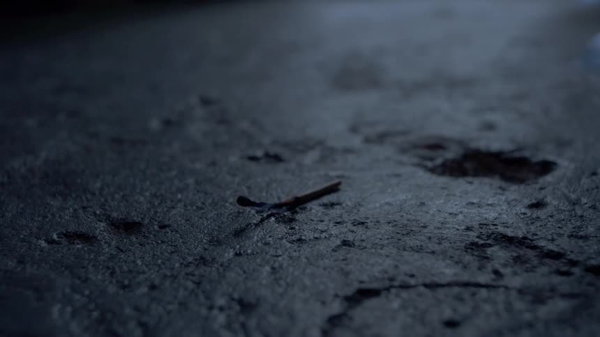 A match is burning out as it lies on the ground outside