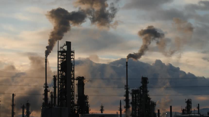 Smoke is rising from the industrial plant at sunset