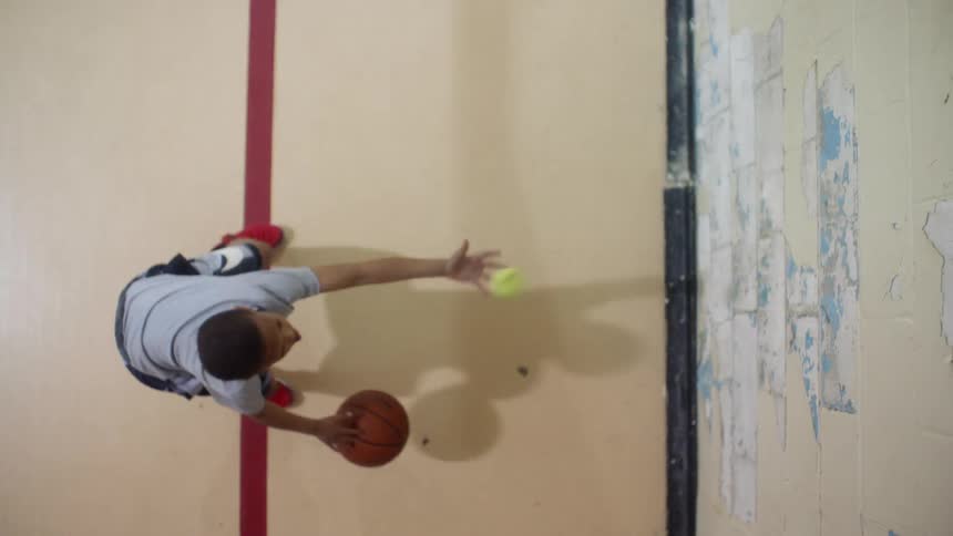 A boy is practicing his basketball dribbling skills inside during the day